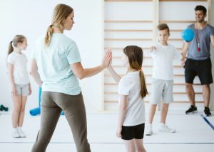Girl doing high five with her teacher during physical education at school