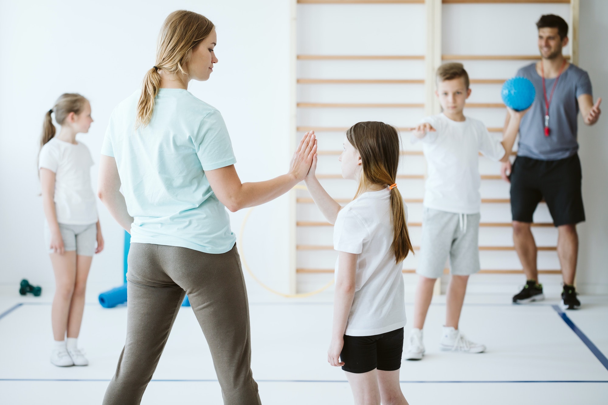 Girl doing high five with her teacher during physical education at school